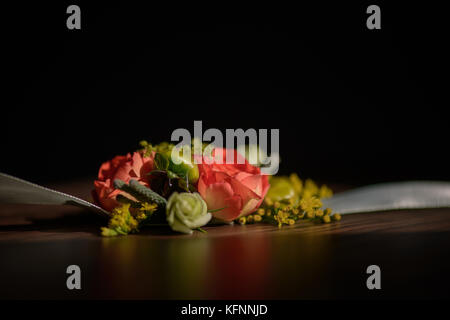 Nozze centrotavola floreali con una rosa rossa al suo nucleo contro uno sfondo scuro Foto Stock