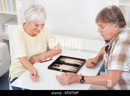 Felice coppia senior a giocare il gioco del Backgammon a casa Foto Stock