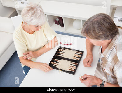 Felice coppia senior a giocare il gioco del Backgammon a casa Foto Stock