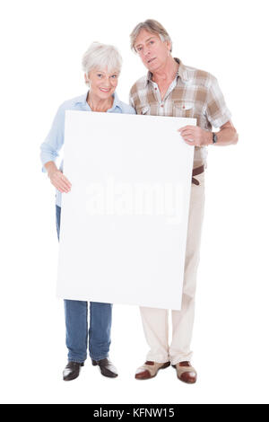 Senior coppia adorabile che tiene insieme un vuoto scheda bianca su sfondo bianco Foto Stock