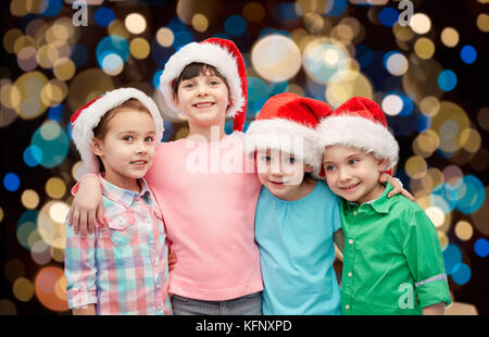 Felici i bambini piccoli in cappelli di Babbo Natale avvolgente Foto Stock