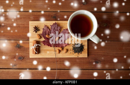 Tazza di tè, maple leaf e mandorla sul pannello di legno Foto Stock