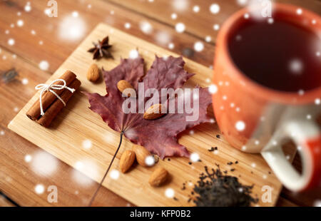 Tazza di tè, maple leaf e mandorla sul pannello di legno Foto Stock