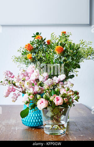 Wild Bunch di fiori in diversi vasi di legno sul tavolo da cucina Foto Stock
