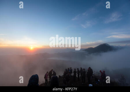 La nebbia si sposta attorno alla vetta del monte Batur All'alba con il Monte Agung in background. Foto Stock
