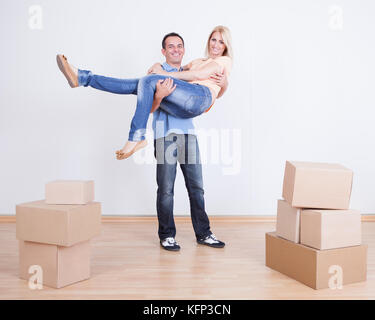 Ritratto del marito tenendo la moglie nella nuova casa, interni Foto Stock