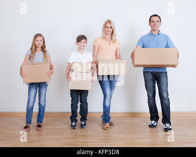 I genitori e i due bambini con scatole di cartone, in interni Foto Stock