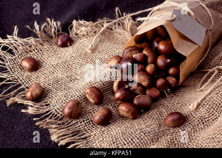 Castagne commestibili - di un sacco di fresco, materie castagne spruzzata sul tavolo Foto Stock