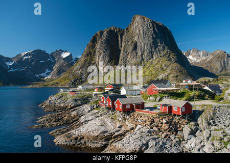 Pesca rosso di capanne di hamnoy isola con le montagne sullo sfondo in Lofoten, Norvegia Foto Stock