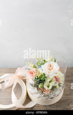 Regalo con fiori freschi. bouquet di fiori misti in vaso in plastica. in piedi sulla scrivania di tavole di legno Foto Stock