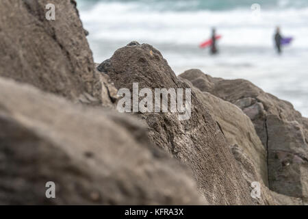 Rocce con surfers in background Foto Stock