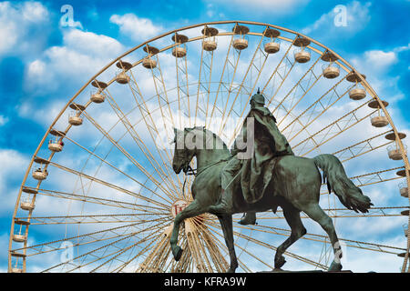 ESSEN, Germania - 30 Ottobre 2017: Il Natale ruota panoramica Ferris è già installato e constrasts con la famosa statua equestre sulla piazza del castello di downtown Foto Stock