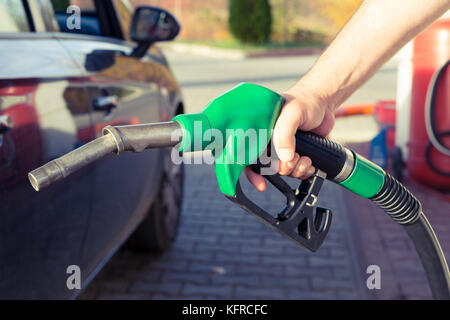 Man mano che tiene la pompa di benzina in una stazione di benzina per riempire il serbatoio o per fare rifornimento di combustibile costoso concetto con aumento di prezzo Foto Stock