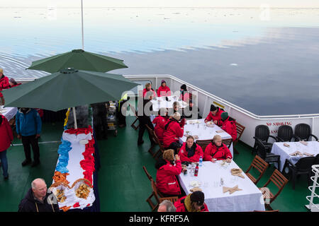 G avventure nave da crociera passeggeri mangiare fuori sul ponte la vela attraverso gelide acque artiche off Spitsbergen costa nel Mare di Norvegia. Svalbard, Norvegia Foto Stock