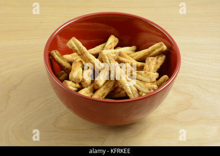 Miele intrecciato pretzel bastoncini snack in rosso ciotola sul tavolo di legno Foto Stock