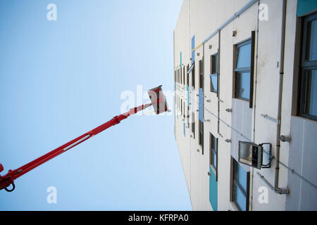 Cherry picker sollevamento elevato a fianco di un blocco a torre di appartamenti del consiglio per la manutenzione in Galles, NEL REGNO UNITO. Foto Stock