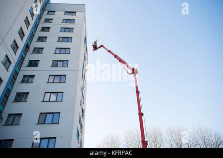 Cherry picker sollevamento elevato a fianco di un blocco a torre di appartamenti del consiglio per la manutenzione in Galles, NEL REGNO UNITO. Foto Stock