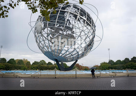 Una donna sotto la pioggia sotto un ombrello vicino ai Weiwei installazione presso l'Unisfera nel lavaggio, Queens, a New York City. Foto Stock