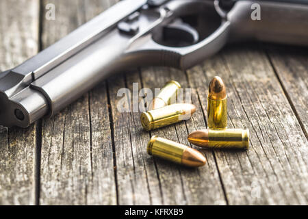9mm proiettili di pistola e revolver sul vecchio tavolo in legno. Foto Stock