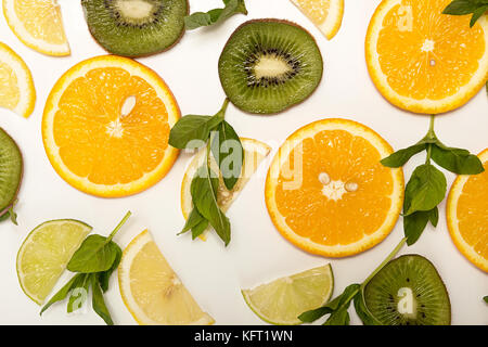 Agrumi, kiwi e menta su sfondo bianco. Fette di frutta di arancia, limone, calce, menta, kiwi vista dall'alto. Vista da sopra. Lay piatto Foto Stock