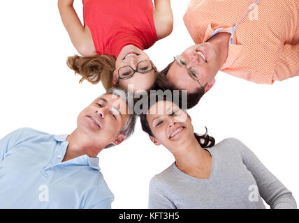 Immagine concettuale di quattro sorridente di mezza età amici rivolta verso l'interno con le loro teste insieme che guarda la telecamera isolato su bianco Foto Stock