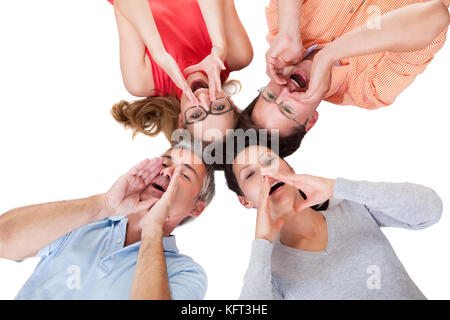 Immagine concettuale di quattro persone di mezza età amici chiamando fuori con le loro mani per le loro bocche e le loro teste insieme isolato su bianco Foto Stock
