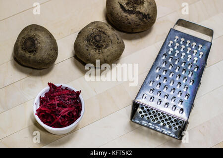 Barbabietole grattugiato sui trucioli. tavolo da pranzo in legno. sfondo nero. Foto Stock