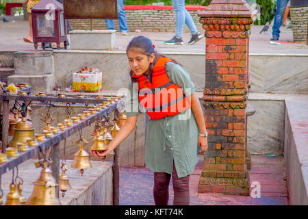 Pokhara, Nepal ottobre 10, 2017: unidentified giovane donna toccando le campane di diverse dimensioni appesi in barahi taal mandir tempio, pokhara, Nepal Foto Stock