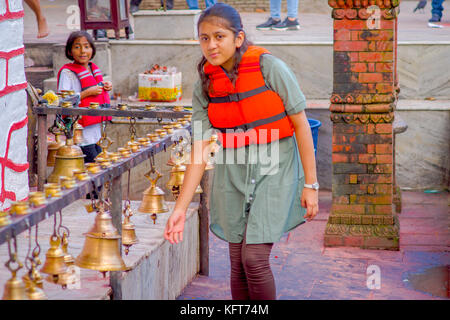 Pokhara, Nepal ottobre 10, 2017: unidentified giovane donna toccando le campane di diverse dimensioni appesi in barahi taal mandir tempio, pokhara, Nepal Foto Stock