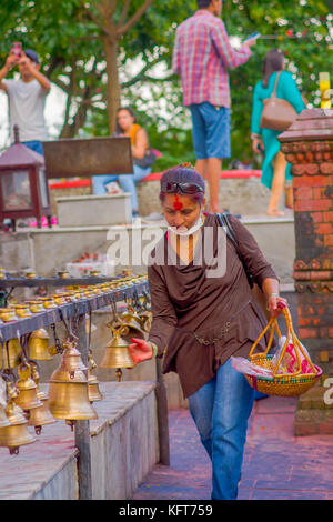 Pokhara, Nepal ottobre 10, 2017: unidentified giovane toccando le campane di diverse dimensioni appesi in barahi taal mandir tempio, pokhara, Nepal Foto Stock