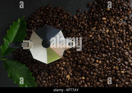 Tazza di caffè e caffè in grani con foglie su sfondo nero Foto Stock