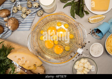 Sovraccarico di frittata ingredienti quiche vegetariana dieta pasto. Le uova in una terrina le uova di quaglia, latte, formaggio mozzarella, gouda, pomodoro, spinaci, funghi, ch Foto Stock