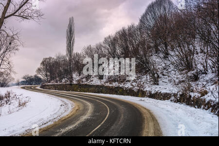 Strada curva sulla serpentina in inverno. pericoloso turnaround sul pendio scivoloso nelle prime ore del mattino Foto Stock