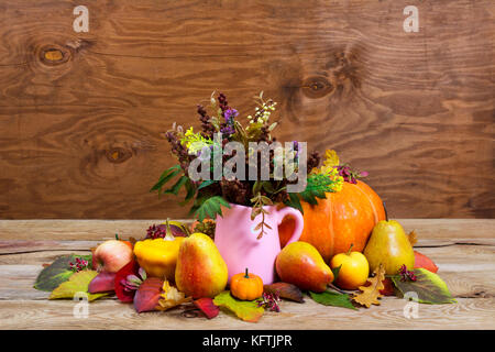 Tabella di ringraziamento centrotavola con caduta di fiori selvatici in rosa vaso Anfora, zucche, mele, pere sul legno rustico sfondo, spazio di copia Foto Stock