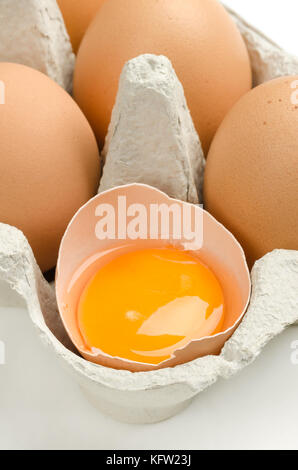 Aprire uovo di pollo in grigio cartone uovo. il bianco d'uovo e il tuorlo d'uovo in guscio crudo leggermente screziato le uova di gallina in carta riciclata scatola uovo. cibo comune. Foto Stock