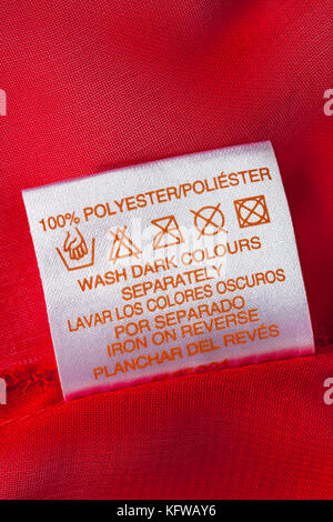 100% poliestere etichetta nella donna abbigliamento rosso lavare con cura i simboli e le istruzioni - lavare i colori scuri separatamente ferro in retromarcia Foto Stock