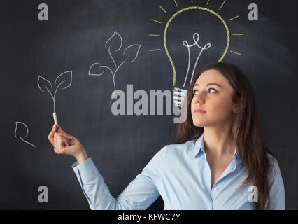 Imprenditrice puntando una foglia disegnò su lavagna Foto Stock