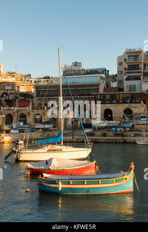 Un tradizionale, dipinto luminosamente, Maltese barca da pesca o luzzu ormeggiata in St Julians Bay Malta Foto Stock