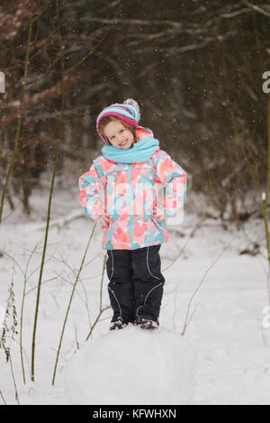 Ragazza fa di pupazzo di neve in inverno park Foto Stock