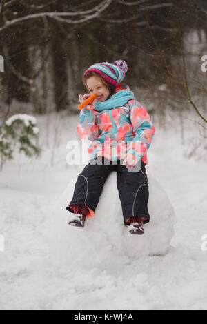 Ragazza fa di pupazzo di neve in inverno park Foto Stock