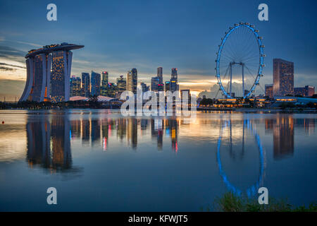 Lo skyline di Singapore con il Marina Bay sands, CBD e il Singapore Flyer, tutto si riflette nella marina bay e illuminato al crepuscolo. Foto Stock