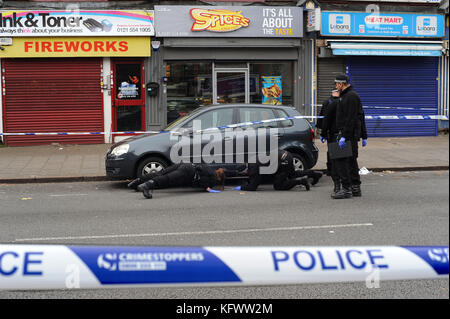 Birmingham, Regno Unito. 1st Nov 2017. Ufficiali della squadra di polizia delle West Midlands, cerca sotto un'auto parcheggiata fuori dalla scena di un incidente che coinvolge sparatorie, nelle vicinanze del ristorante Spices Takeaway sulla Soho Road a Handsworth. Il West Midlands Ambulance Service è stato chiamato la sera precedente intorno alle 10,50, rispondendo ad un assalto segnalato al di fuori del takeaway. Parte di Soho Road è stata chiusa per oltre 12 ore mentre la polizia effettua una serie di ricerche fuori dal ristorante. Credit: Kevin Hayes/Alamy Live News Foto Stock