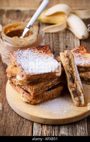 Burro di arachidi e banana toast francesi con zucchero a velo sulla tavola in legno rustico Foto Stock