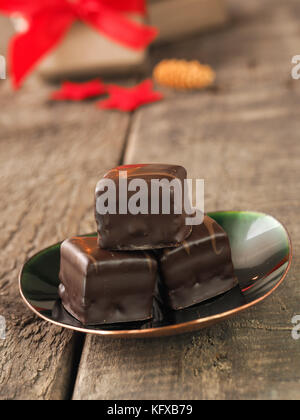 Gustoso cioccolato dolce plinti su una piastra verde, panetteria di Natale o il concetto di pasticceria, confezioni regalo e decorazione di Natale in background Foto Stock