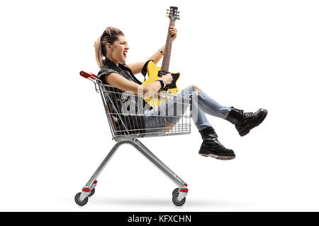 Punk ragazza seduta all'interno di un carrello della spesa e suonando una chitarra elettrica isolata su sfondo bianco Foto Stock