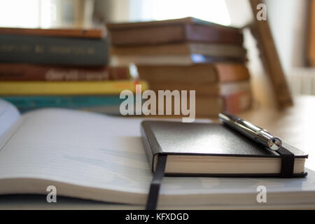 Un notebook con una panoramica e un libro in background. Foto Stock