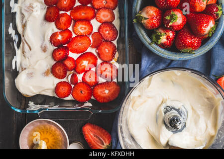 Dolce alle fragole rendendo. piatto con fette di frutti di bosco e crema scuro su sfondo rustico, vista dall'alto Foto Stock