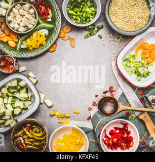 Un sano piatto vegetariano preparato con dadini di formaggio feta, tagliare le verdure in ciotole, orzo perlato , cucina cucchiaio e coltello da cucina, vista dall'alto. Pulire d Foto Stock