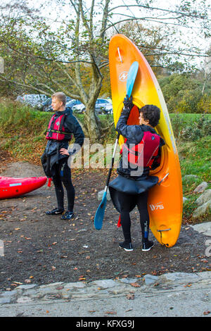 Un paio di giovani uomini che liberano le loro attrezzature nautiche dopo un pomeriggio di allenamento in kayak sul lago nel Castlewellan Forest Park, Irlanda del Nord Foto Stock