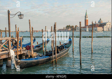 Gondole ormeggiate presso Riva degli Schiavoni a San Marco, Venezia, Italia. La laguna veneta e l'isola di San Giorgio maggiore sullo sfondo. Foto Stock